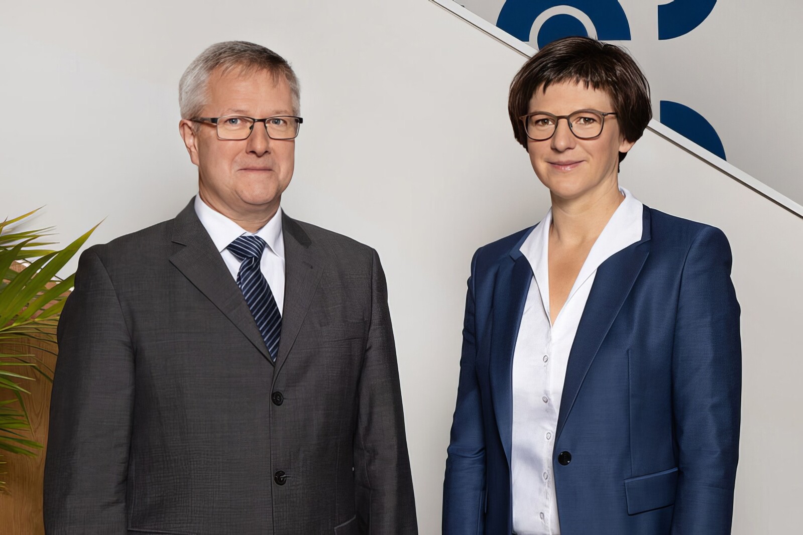 Herr Schumacher und Frau Göltzer (Hauptgeschäftsführung) stehen vor einer weißen Wand